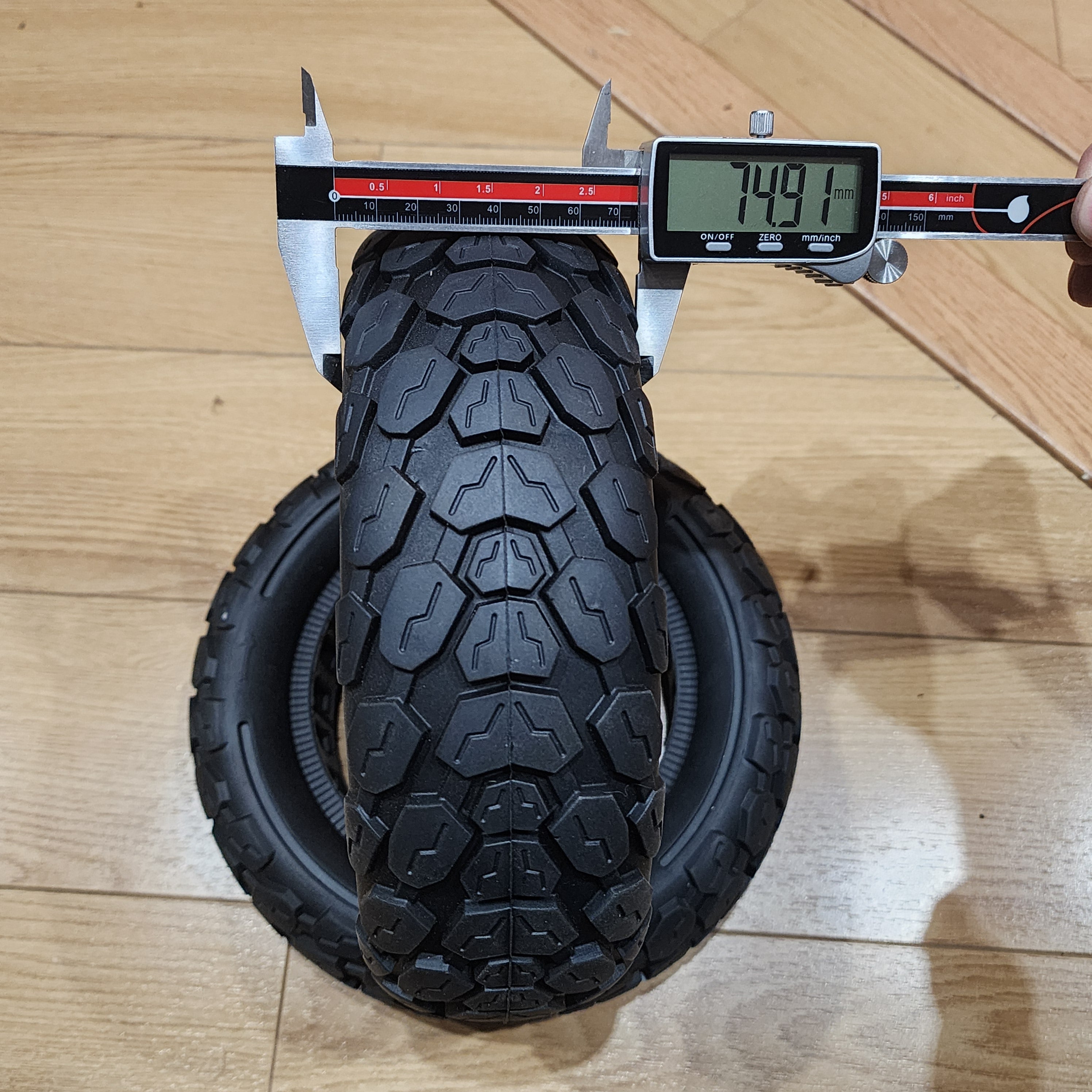 74.91mm displayed on the calipers measuring the width of thee electric scooter tires