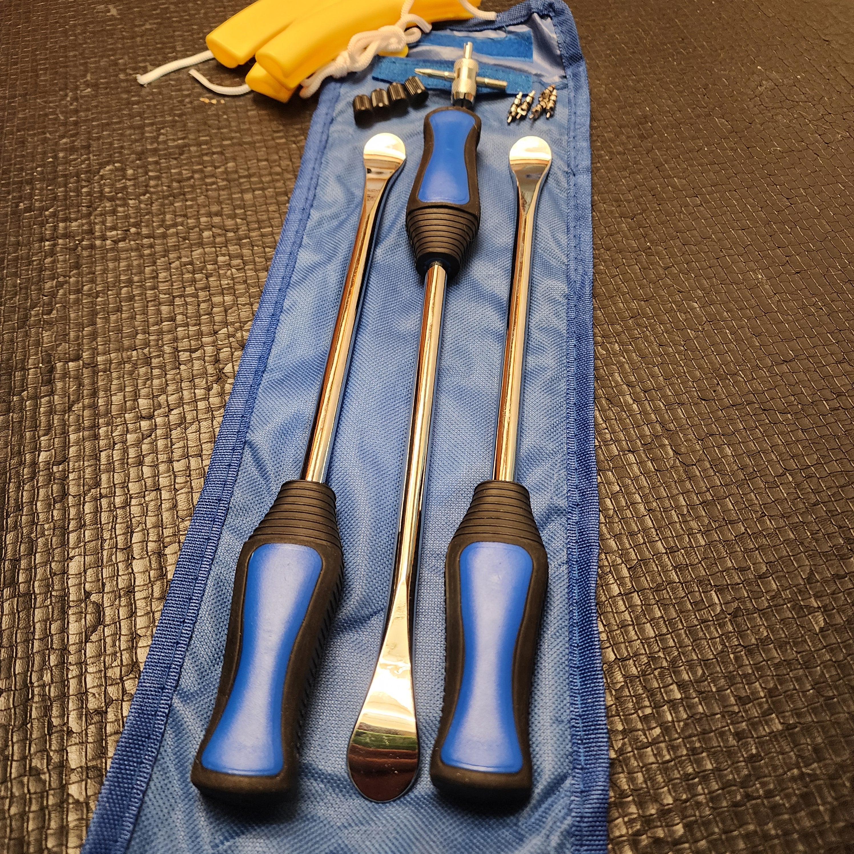 A 15piece tire lever set with blue handles and metal rods, displayed in a blue carrying case on a dark textured surface.